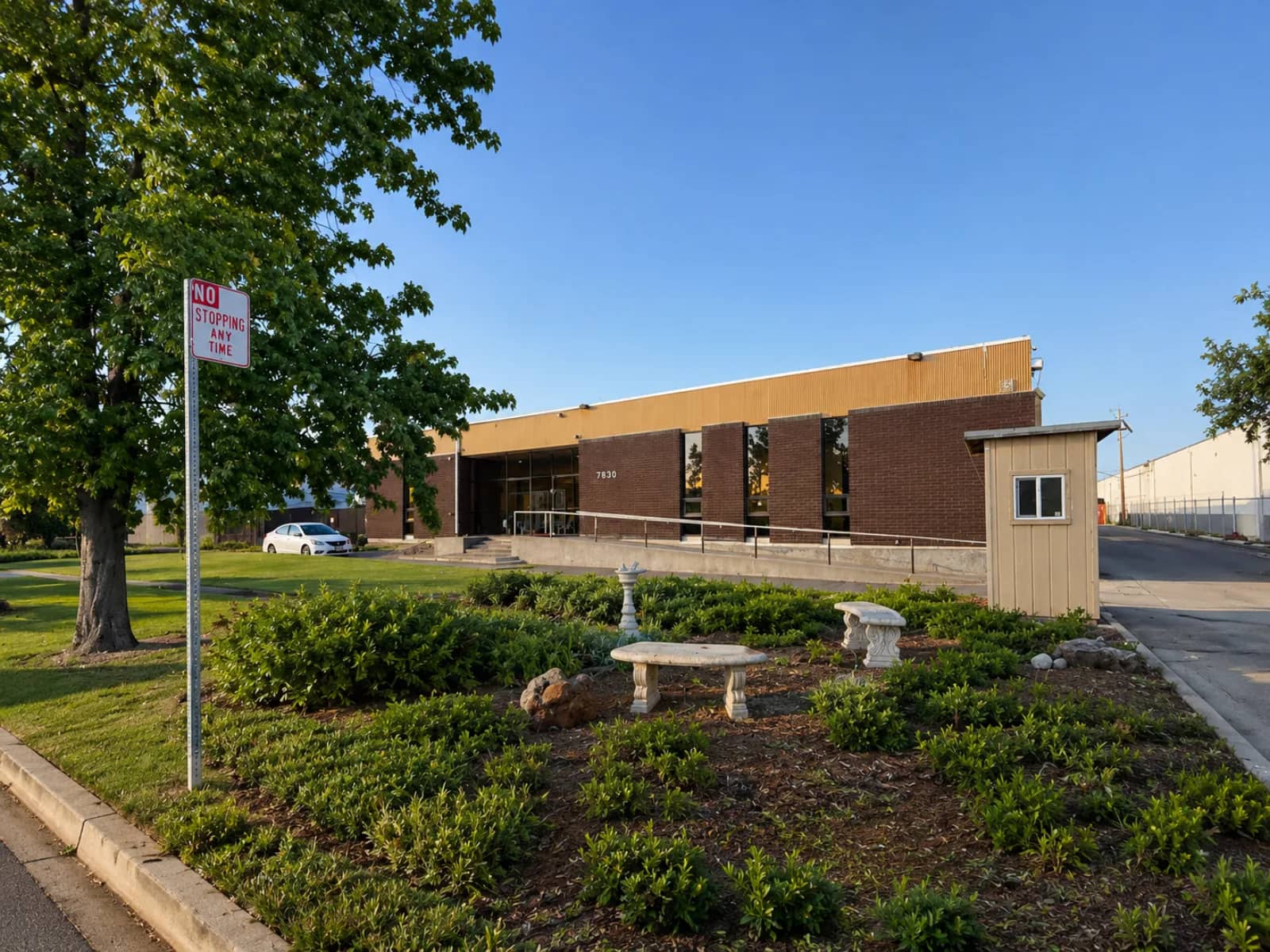 Front of MyShahada Islamic Center at 7850 Edgewater Drive in Oakland, California: a brick building behind a landscaped garden with stone benches